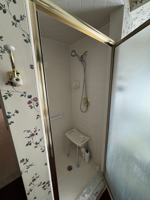 bathroom with a stall shower and wallpapered walls