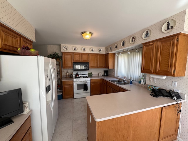 kitchen with white appliances, wallpapered walls, a peninsula, light countertops, and a sink