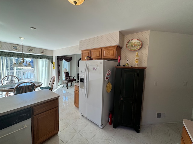 kitchen with visible vents, brown cabinetry, white fridge with ice dispenser, dishwashing machine, and wallpapered walls