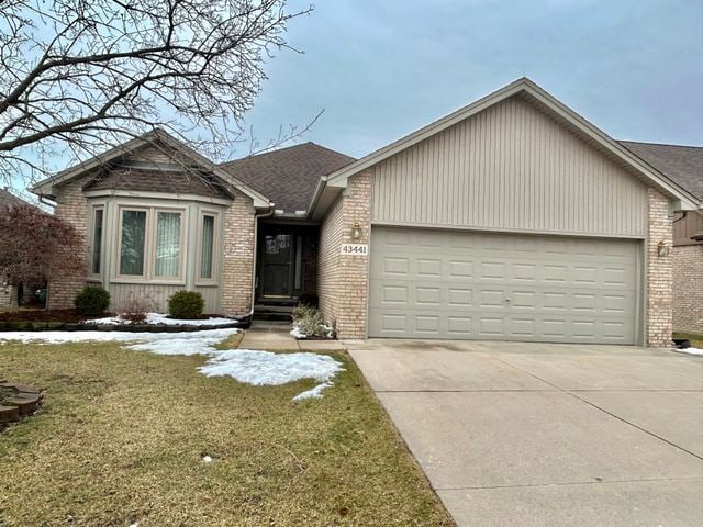 view of front of house with a garage, driveway, a front lawn, and brick siding