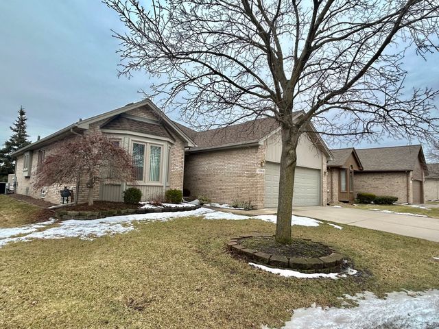 view of front of home with concrete driveway, brick siding, a yard, and an attached garage