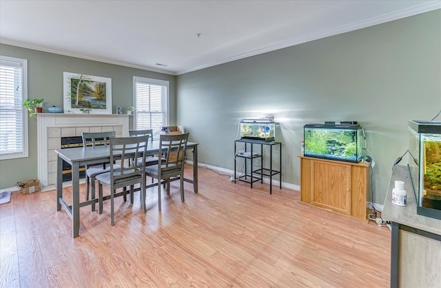 dining space with a tiled fireplace, a healthy amount of sunlight, and crown molding