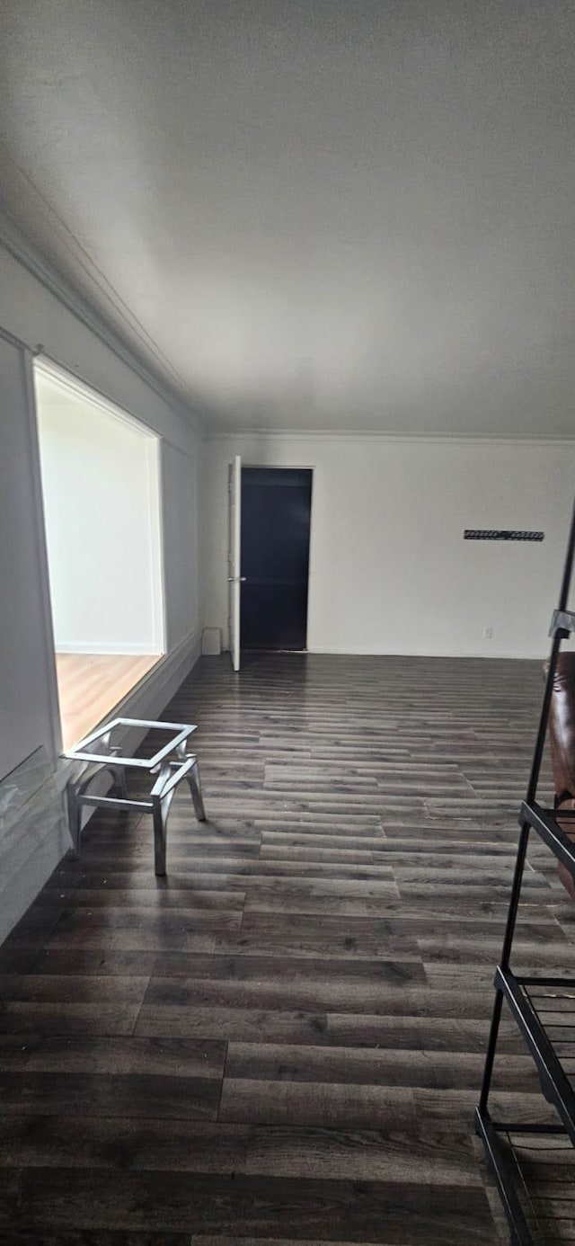 empty room featuring dark wood-type flooring and crown molding