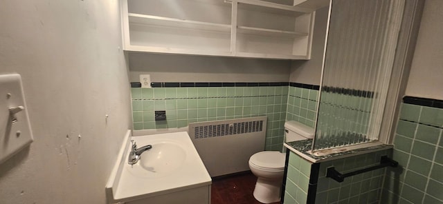 bathroom featuring tile walls, radiator heating unit, vanity, and toilet