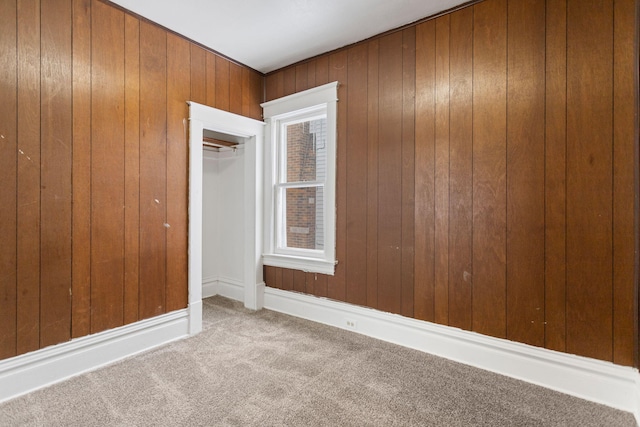 carpeted empty room with wood walls