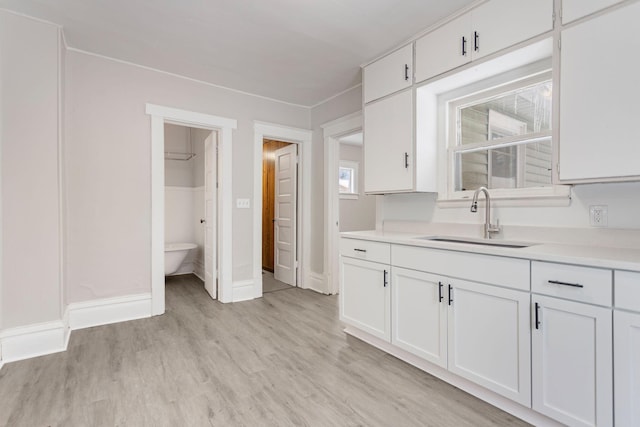 kitchen featuring white cabinets, light hardwood / wood-style floors, and sink