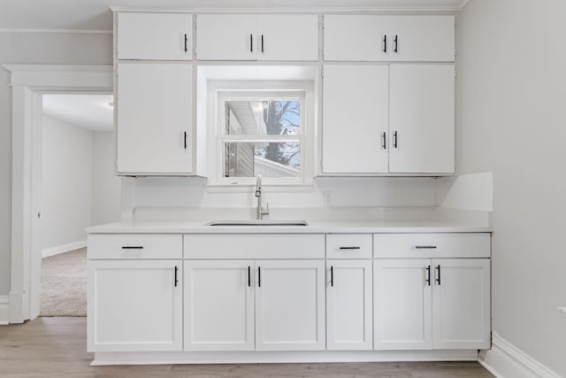 kitchen with white cabinets, light hardwood / wood-style flooring, and sink