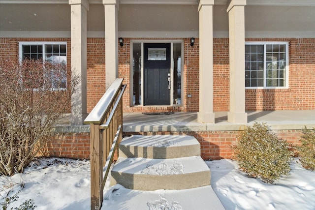 snow covered property entrance with a porch