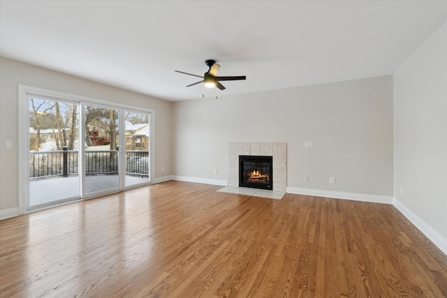 unfurnished living room with a tiled fireplace, light hardwood / wood-style flooring, and ceiling fan