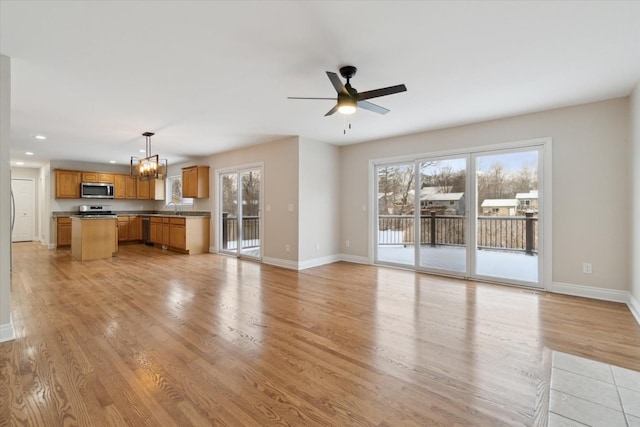 unfurnished living room featuring sink, ceiling fan with notable chandelier, and light hardwood / wood-style flooring