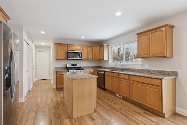 kitchen with sink, appliances with stainless steel finishes, a center island, and light hardwood / wood-style flooring