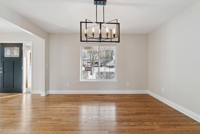 unfurnished dining area featuring a notable chandelier and hardwood / wood-style flooring