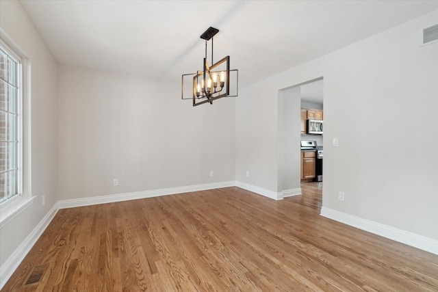 unfurnished room with light hardwood / wood-style flooring and an inviting chandelier