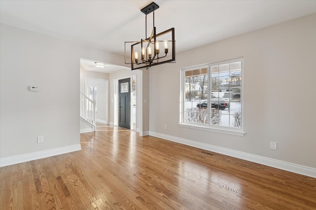 unfurnished dining area with a chandelier and wood-type flooring