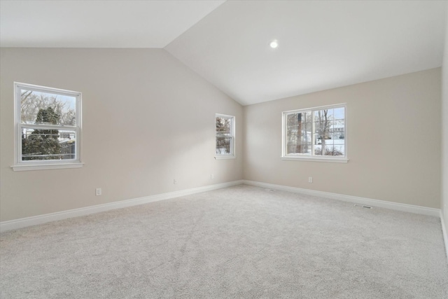 carpeted spare room featuring lofted ceiling and a wealth of natural light