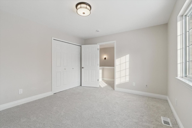 unfurnished bedroom featuring a closet and light carpet