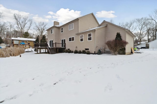 snow covered house with a wooden deck