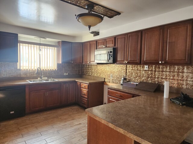 kitchen featuring decorative light fixtures, dishwasher, light hardwood / wood-style floors, kitchen peninsula, and sink