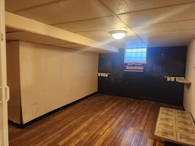 basement with dark wood-type flooring and a drop ceiling