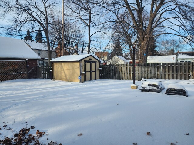 yard covered in snow featuring a storage shed