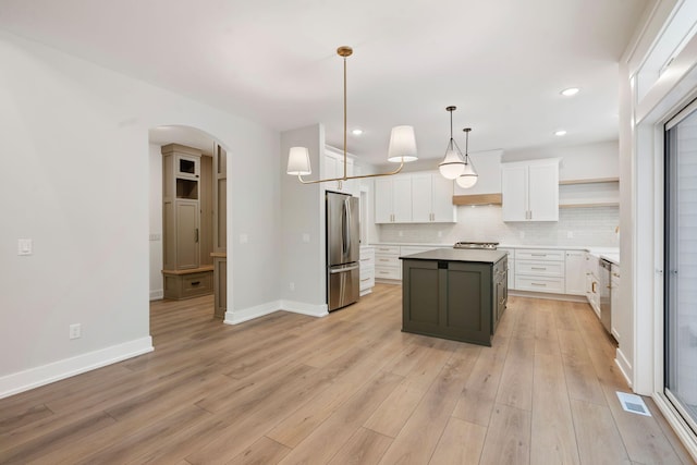 kitchen with stainless steel appliances, white cabinets, a center island, decorative backsplash, and hanging light fixtures