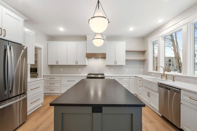 kitchen with a kitchen island, stainless steel appliances, white cabinetry, and hanging light fixtures