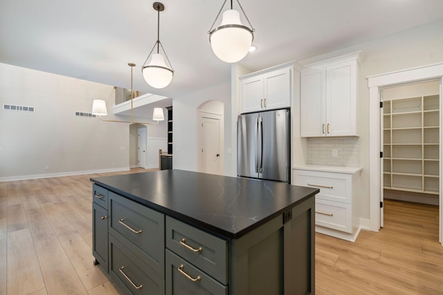 kitchen featuring hanging light fixtures, tasteful backsplash, gray cabinets, white cabinetry, and stainless steel refrigerator