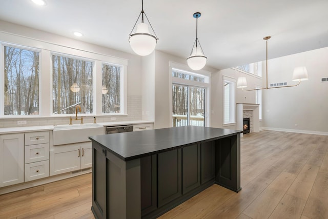 kitchen with white cabinets, dishwasher, decorative backsplash, sink, and decorative light fixtures