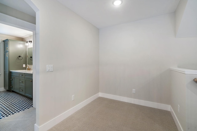 spare room featuring sink and light colored carpet