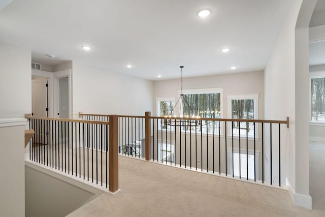 hallway featuring an inviting chandelier and carpet floors