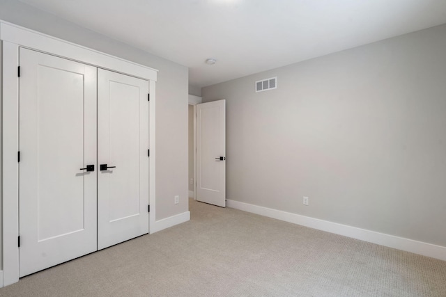 unfurnished bedroom with a closet and light carpet