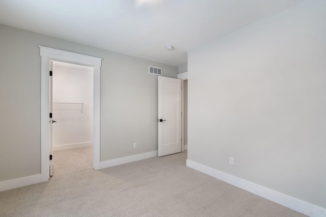 unfurnished bedroom featuring light colored carpet, a closet, and a spacious closet