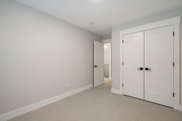 unfurnished bedroom featuring light colored carpet and a closet