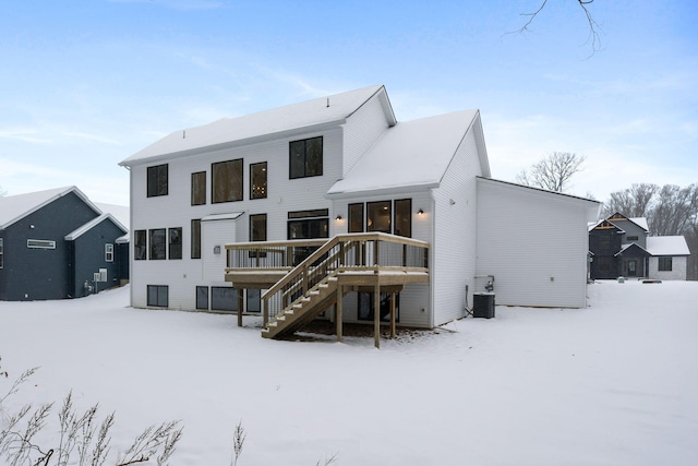 snow covered back of property with central AC and a wooden deck