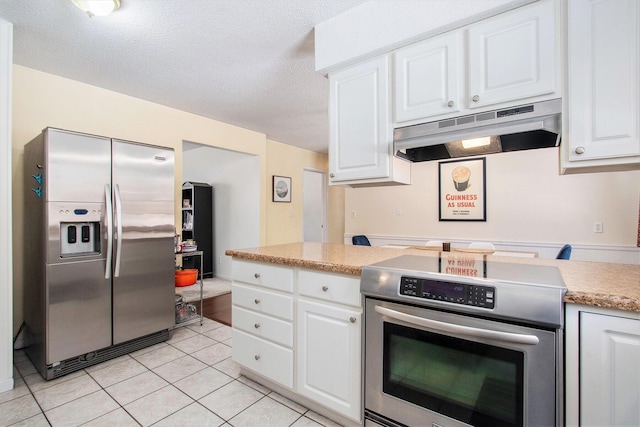 kitchen featuring appliances with stainless steel finishes, white cabinets, a textured ceiling, and light tile patterned floors