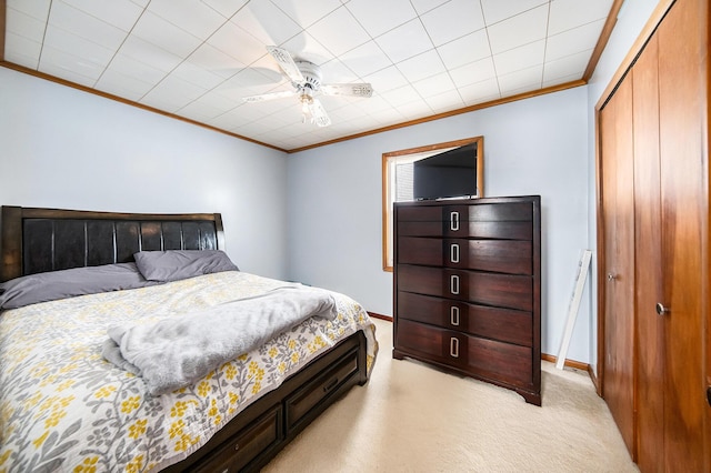 carpeted bedroom with a closet, ceiling fan, and ornamental molding