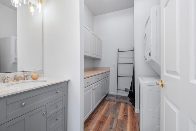 bathroom with stacked washer and clothes dryer, vanity, and hardwood / wood-style flooring