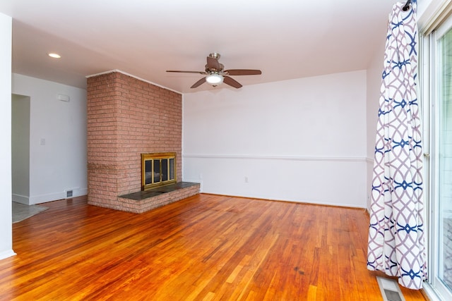 unfurnished living room featuring a brick fireplace, hardwood / wood-style floors, and ceiling fan