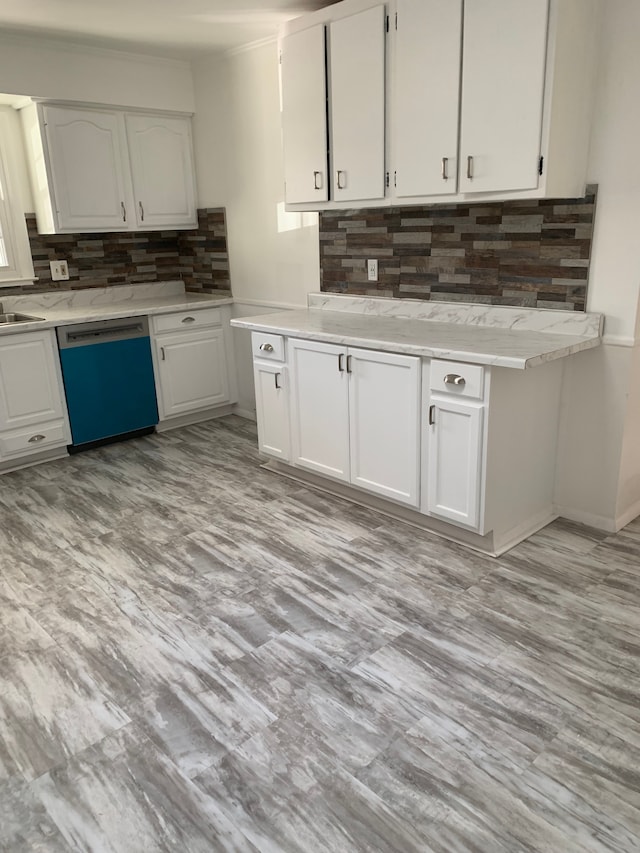 kitchen featuring stainless steel dishwasher, white cabinets, and backsplash