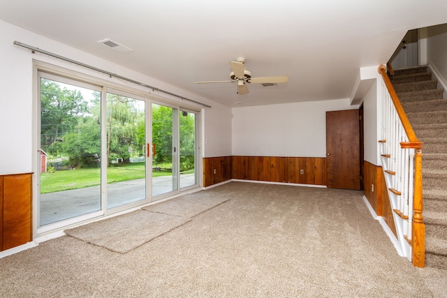 21918 Knudsen Dr, Grosse Ile, MI 48138 - carpeted spare room with stairway, a wainscoted wall, wood walls, and a ceiling fan