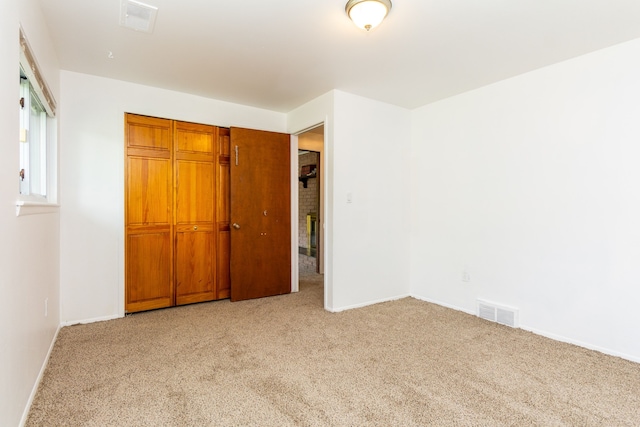 unfurnished bedroom featuring a closet and light colored carpet