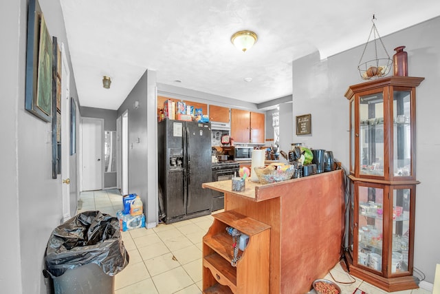 kitchen featuring a kitchen bar, light tile patterned floors, black appliances, and kitchen peninsula