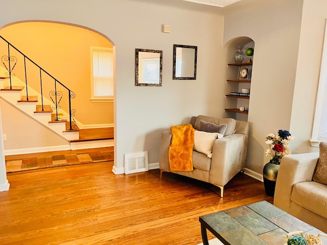 living area with hardwood / wood-style flooring and built in shelves