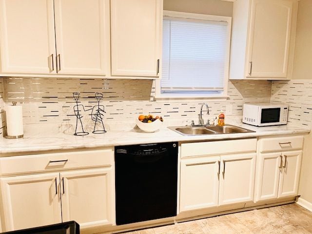 kitchen featuring black dishwasher, tasteful backsplash, light stone counters, and sink