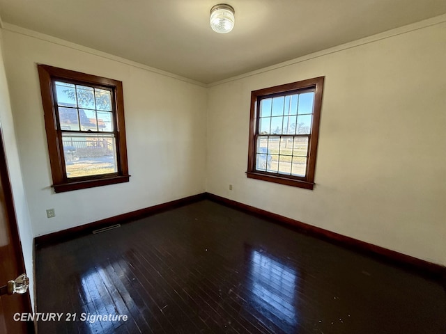 spare room with ornamental molding and dark hardwood / wood-style flooring