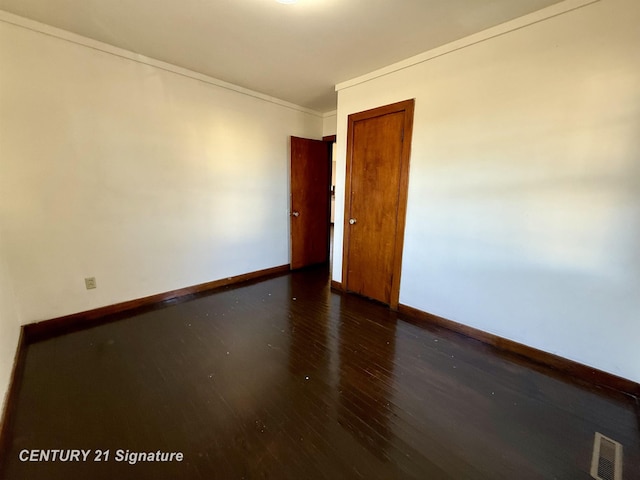 unfurnished room featuring dark wood-type flooring and ornamental molding