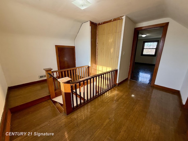 staircase with hardwood / wood-style floors and vaulted ceiling