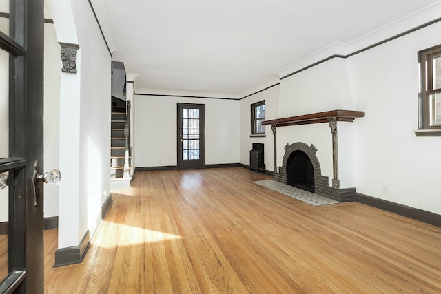 unfurnished living room featuring a brick fireplace, light hardwood / wood-style flooring, and ornamental molding