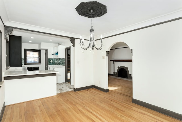 unfurnished dining area with light hardwood / wood-style floors, ornamental molding, and a notable chandelier