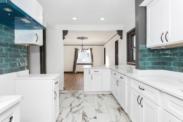 kitchen with backsplash, extractor fan, white cabinetry, and pendant lighting